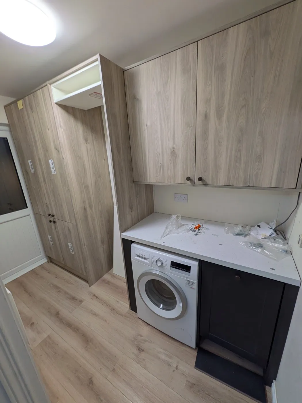 Fitted utility room with oak-effect tall units and a washing machine under the worktop