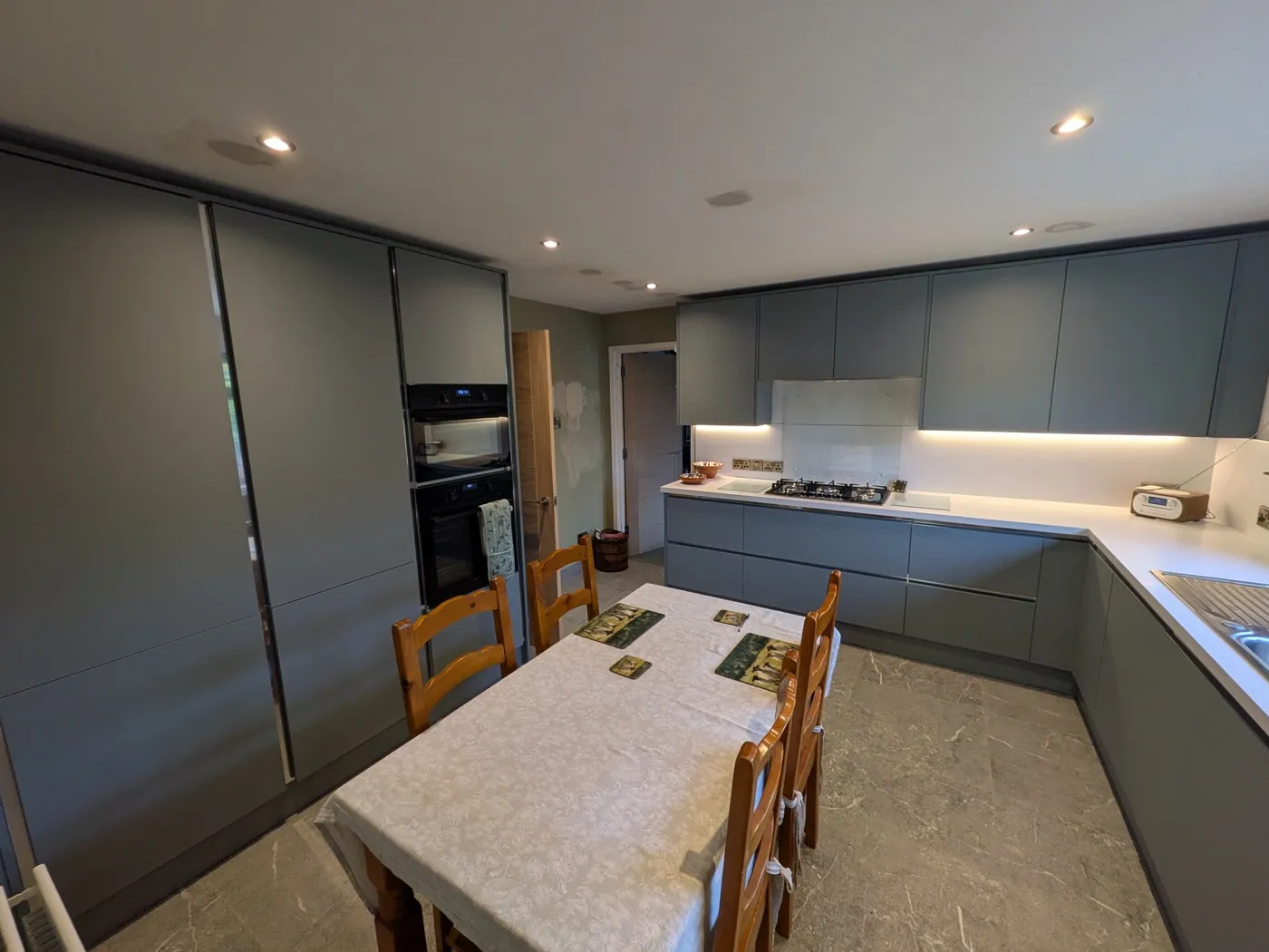 Handleless grey kitchen with integrated ovens and under-cabinet lighting, fitted by McGibbon Construction