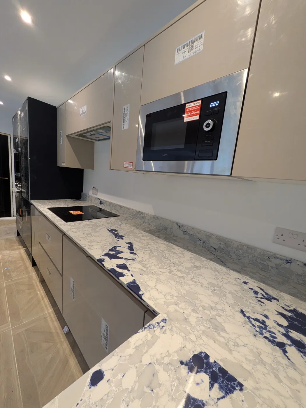 Cashmere gloss kitchen with a built-in microwave and a white and navy granite worktop
