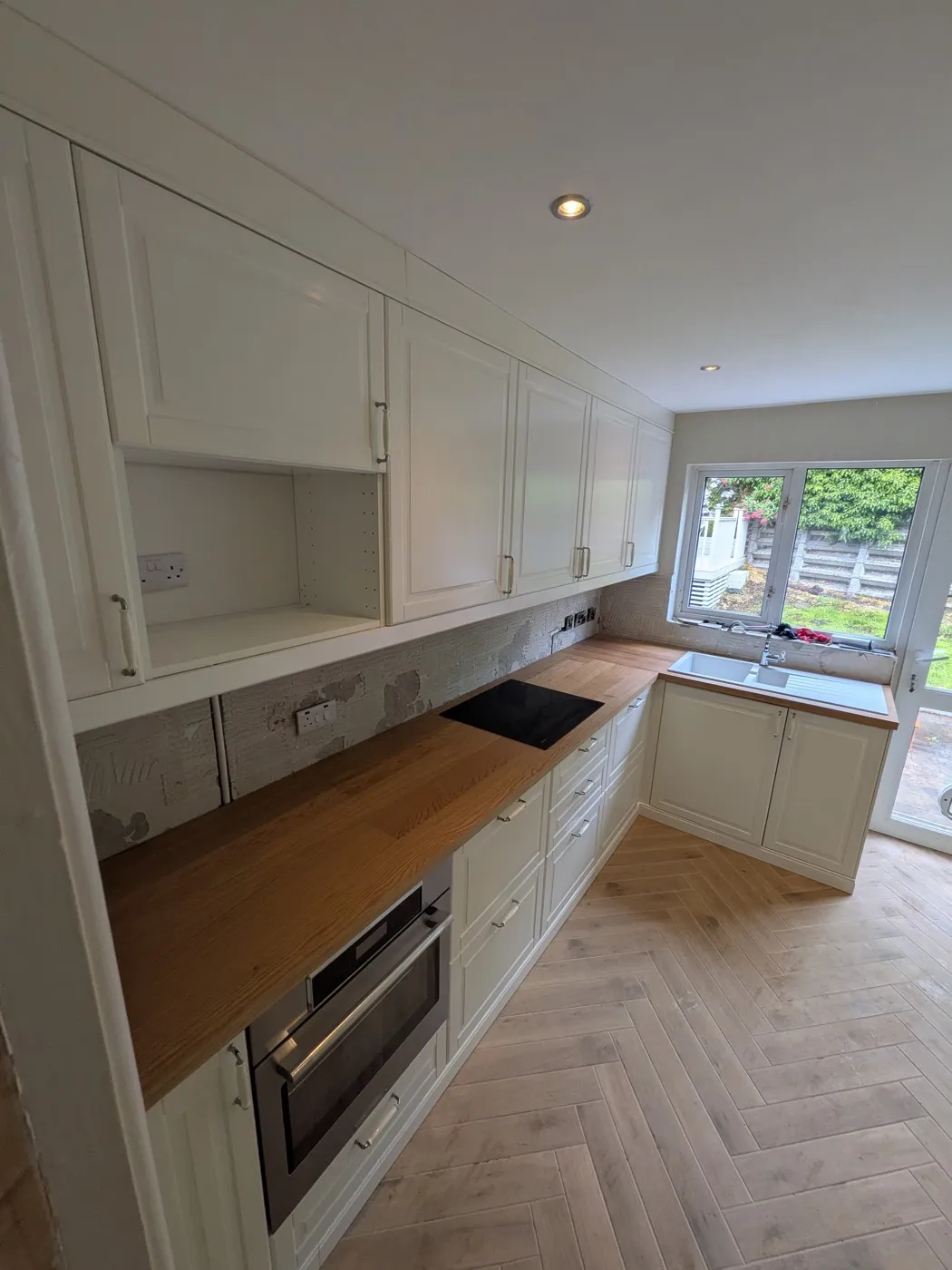 Cream shaker kitchen with solid timber worktops and a herringbone floor