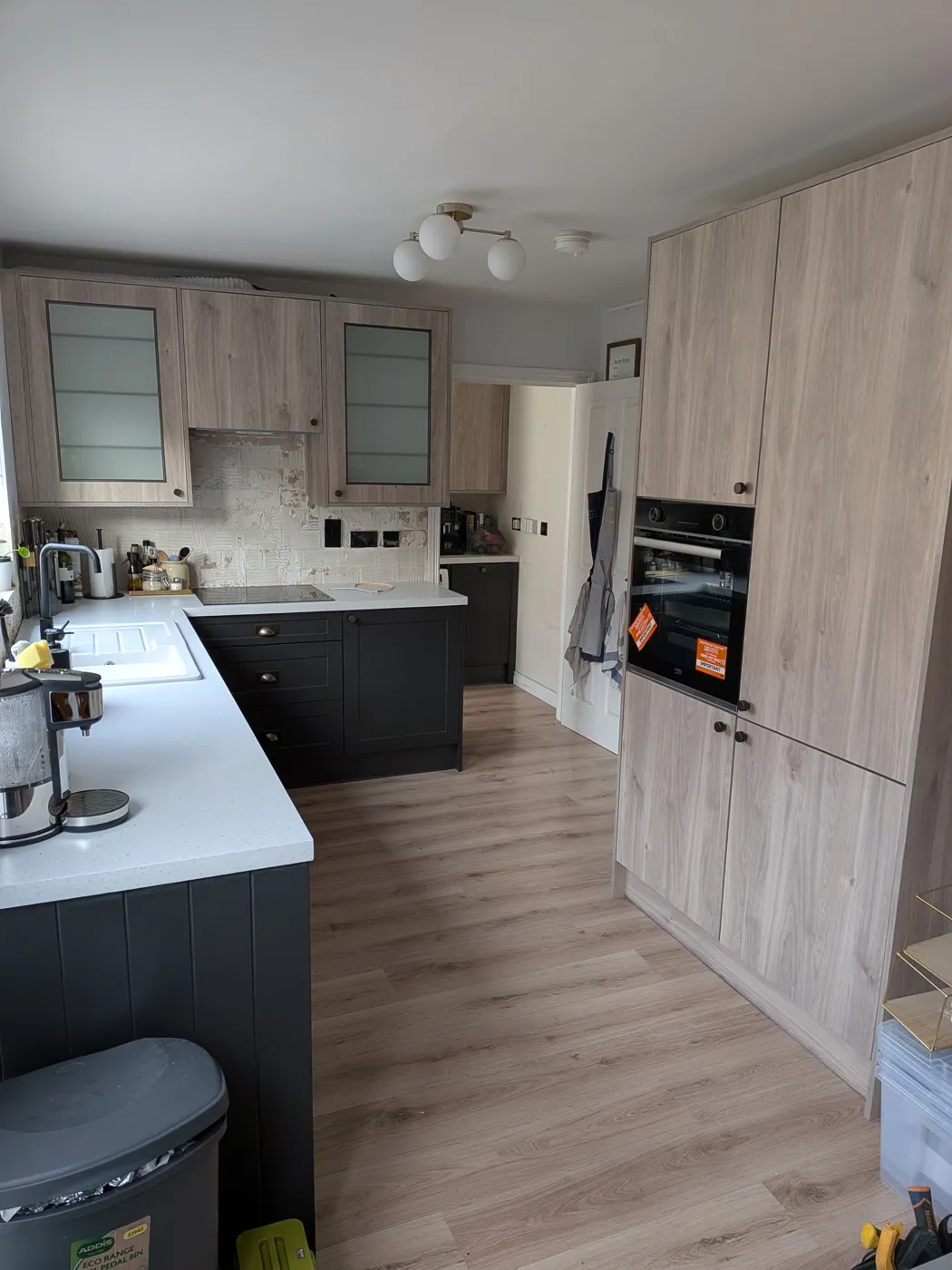 Two-tone kitchen with light oak-effect tall units and navy base cabinets