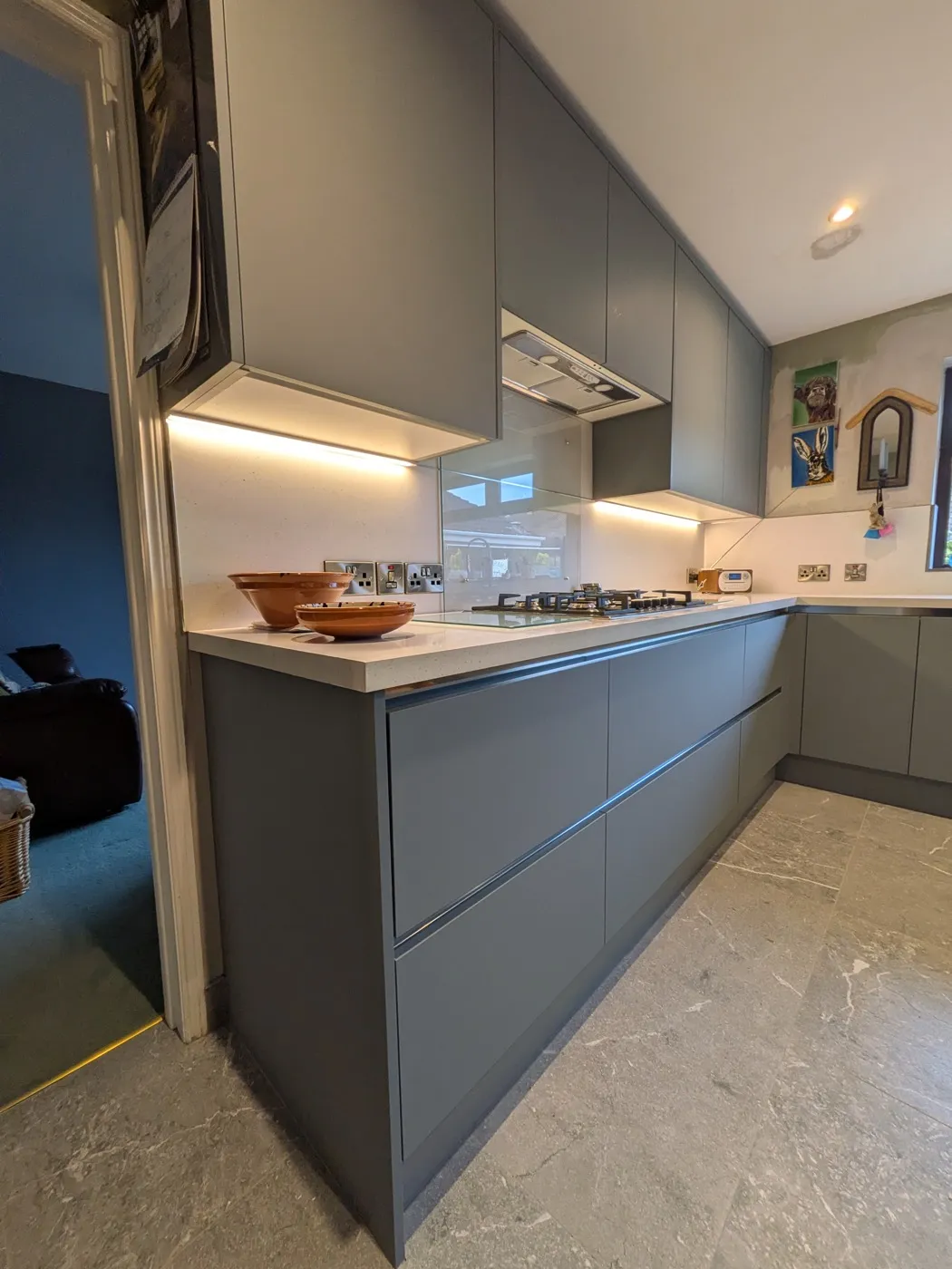 Grey handleless kitchen with under-cabinet lighting and a gas hob